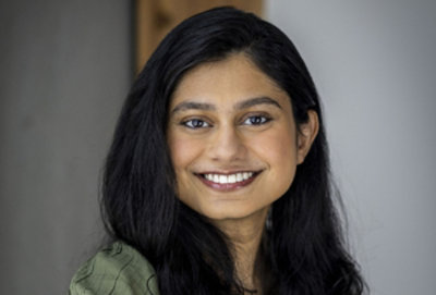 Smiling woman with long dark hair, wearing a green top.