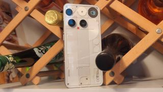 The Nothing Phone (3) leaning on a wine rack.